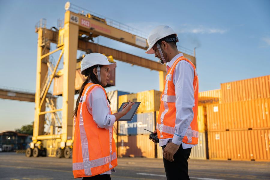 Trabajadores portuarios con casco coordinando una operación junto a contenedores